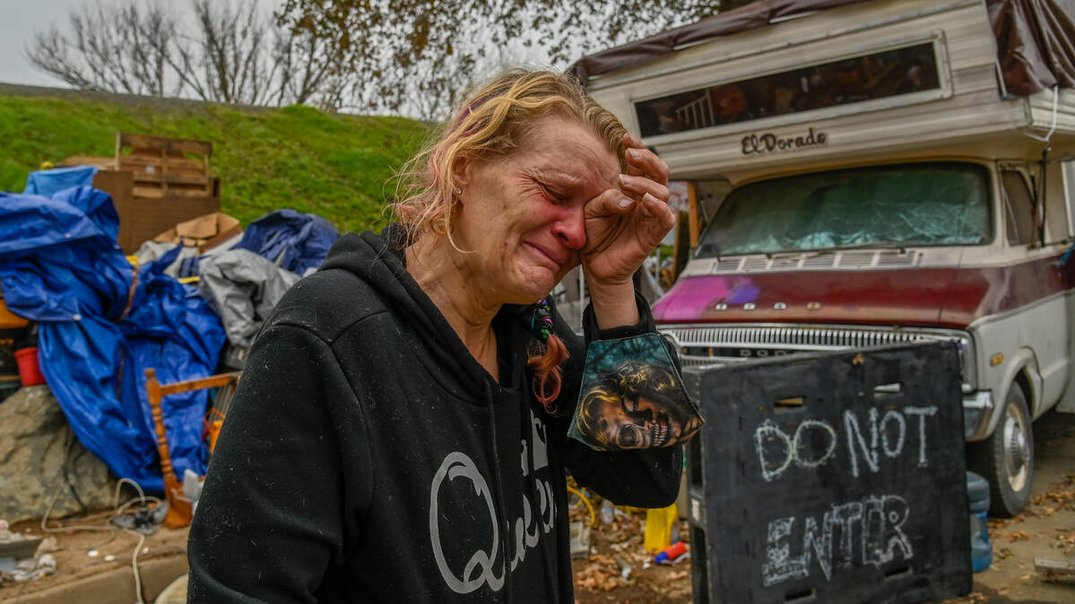 Alice'a Stanley, de 46 años, una madre de dos hijos que acaba de ser dada de alta del hospital donde estaba siendo tratada por neumonía, se seca las lágrimas mientras trata de averiguar cómo llevar su caravana a otro lugar mientras los equipos de la ciudad remueven los vehículos y remolques a lo largo de Lathrop Way, el lunes 6 de diciembre de 2021. "Me siento miserable y acabo de regresar del hospital anoche, tuve neumonía tratando de limpiar estas cosas y salir de ella lo suficientemente rápido", dijo Stanley. "Me puso enferma".