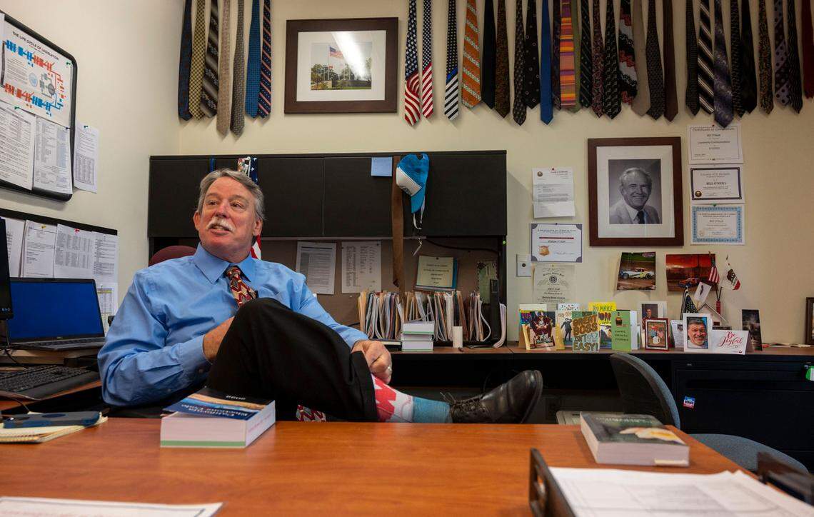 Bill O’Neill, registrar of voters for El Dorado County, shows off his socks fashioned after the movie “Jaws” earlier this month while sitting in his office filled with colorful ties, many that belonged to his father. O’Neill gives guided tours of his office in an effort to help voters understand the election process.