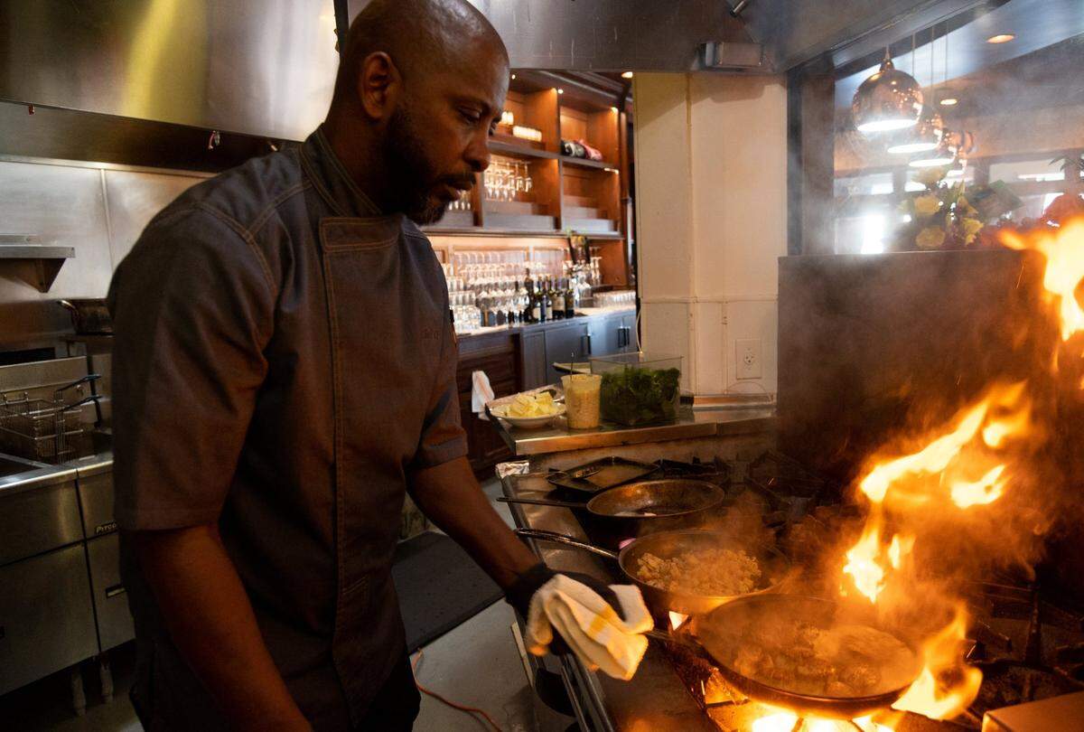 Quentin “Chef Q” Bennett makes pan-seared scallop with crab hash cakes, sauteed spinach and garlic beurre blanc at Q1227 restaurant in Roseville.