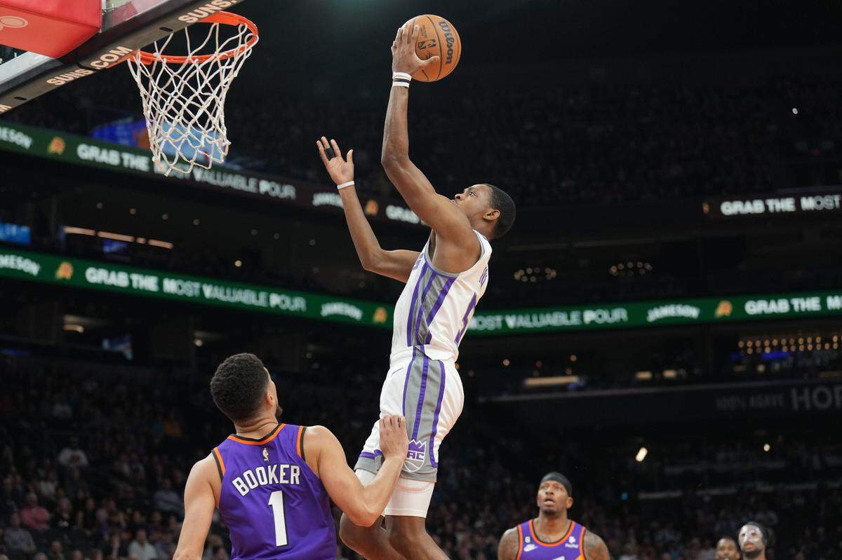Sacramento Kings guard De’Aaron Fox (5) puts up a layup over Phoenix Suns guard Devin Booker (1) during the first half at Footprint Center on Saturday.