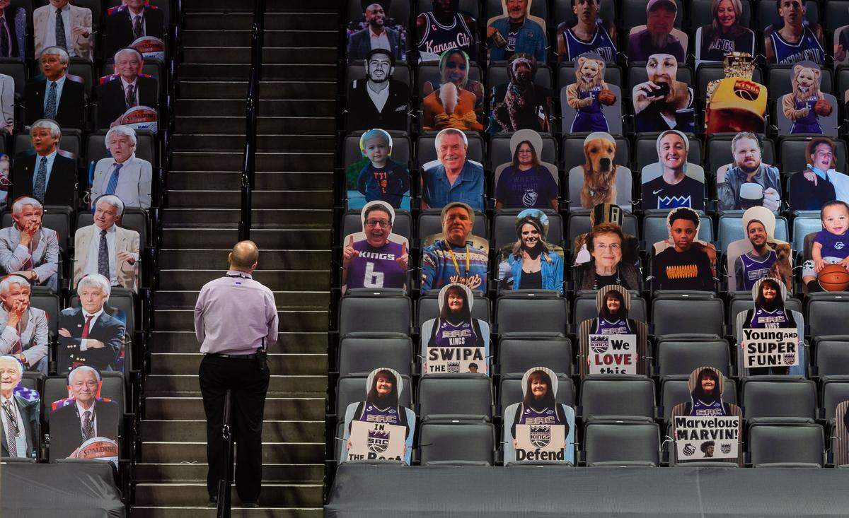 An usher stands on the stairs, as in previous seasons, looking at photos of fans in attendance – and a section of Jerry Reynolds images, at left – as the Sacramento Kings play the Golden State Warriors in their final preseason game Thursday, Dec. 17, 2020, at Golden 1 Center in Sacramento.