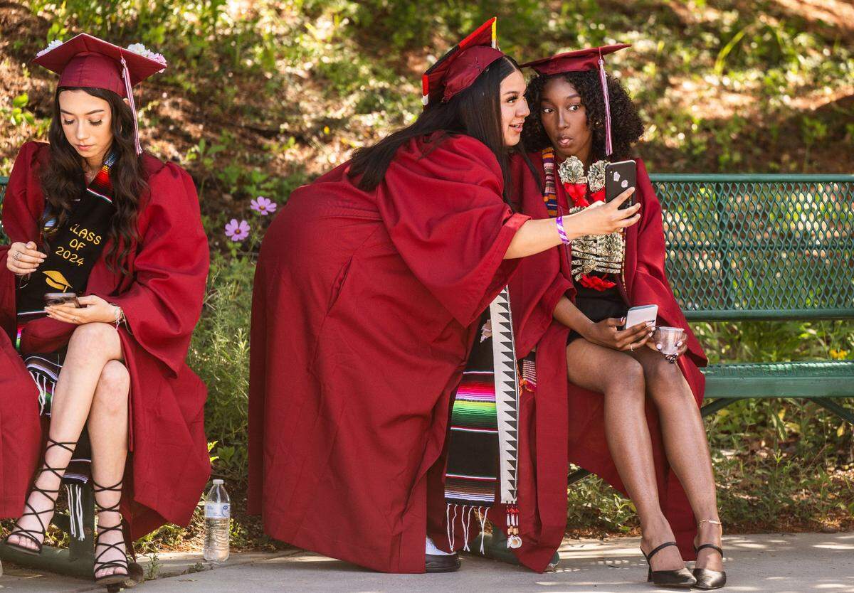 Esmeralda Castanon, center, takes a selfie with Alannah Crump during their C.K. McClatchy commencement ceremony on Tuesday at Sutter Health Park.