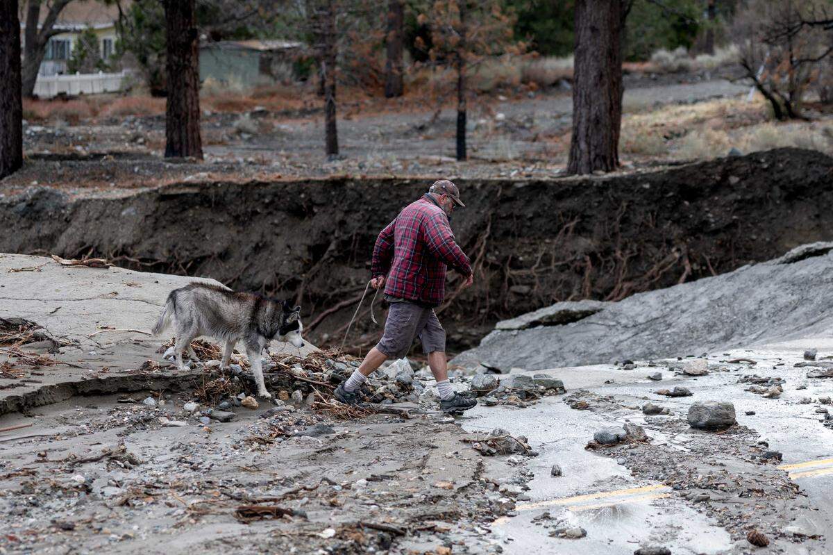 A man walks through storm damage in Wrightwood on Christmas Day.