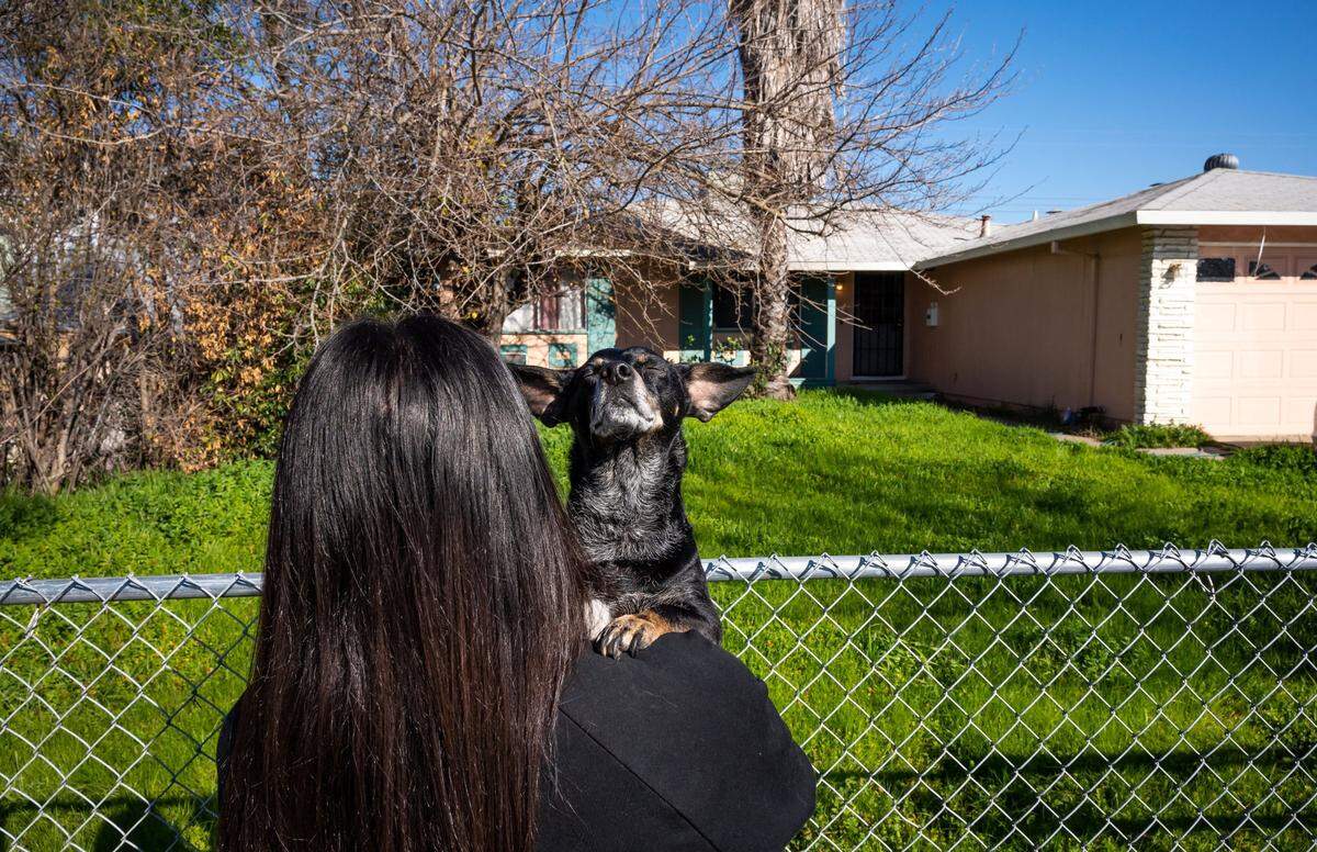 Rachel Walker holds her dog, Yoda, in January as she looks back at the Rancho Cordova home where she has lived for five years. She worries about looking for a new rental in the current market. “On paper everything looks great… but the same situation goes for probably 30 other applicants as well,” she said. “It’s just a fight out there.”