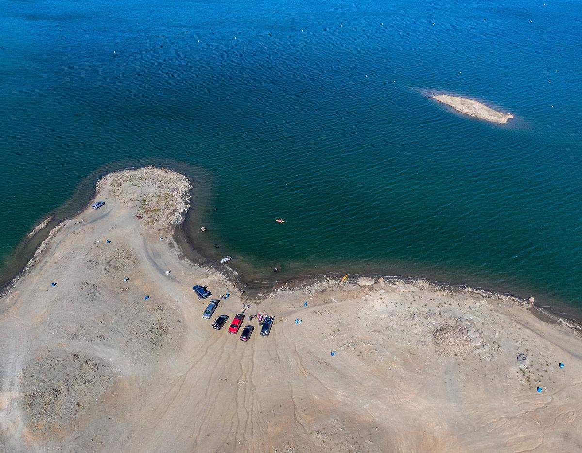 The vehicles of boaters and kayakers cluster at the diminished shoreline of Folsom Lake near the Brown’s Ravine boat ramp in early June last year. One year ago, the lake held less than half of the average amount of water for the time of year.