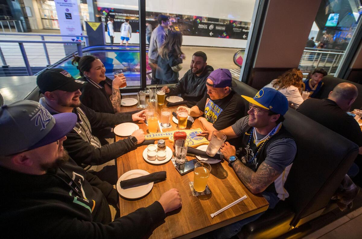 Golden State Warriors fan Michael Rodrigues, right, talks across the table to Sacramento Kings fan Chase Herman, both of Redding, as they have drinks and food at Yard House at DoCo before the two teams play in the NBA basketball game Friday, April 7, 2023, at Golden 1 Center. “They’re all Kings fans except for me,” Rodrigues said, referring to their group of friends from across Northern California. “It’s okay, we still love him,” someone responded, laughing. It was Kings’ last home game of the regular season, but for the first time in years fans are looking forward to seeing the team in the playoffs.