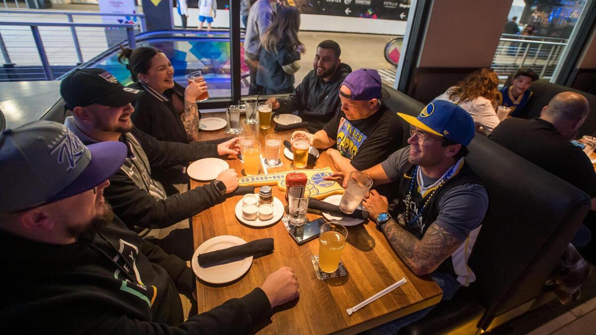 Golden State Warriors fan Michael Rodrigues, right, talks across the table to Sacramento Kings fan Chase Herman, both of Redding, as they have drinks and food at Yard House at DoCo before the two teams play in the NBA basketball game Friday, April 7, 2023, at Golden 1 Center. “They’re all Kings fans except for me,” Rodrigues said, referring to their group of friends from across Northern California. “It’s okay, we still love him,” someone responded, laughing. It was Kings’ last home game of the regular season, but for the first time in years fans are looking forward to seeing the team in the playoffs.