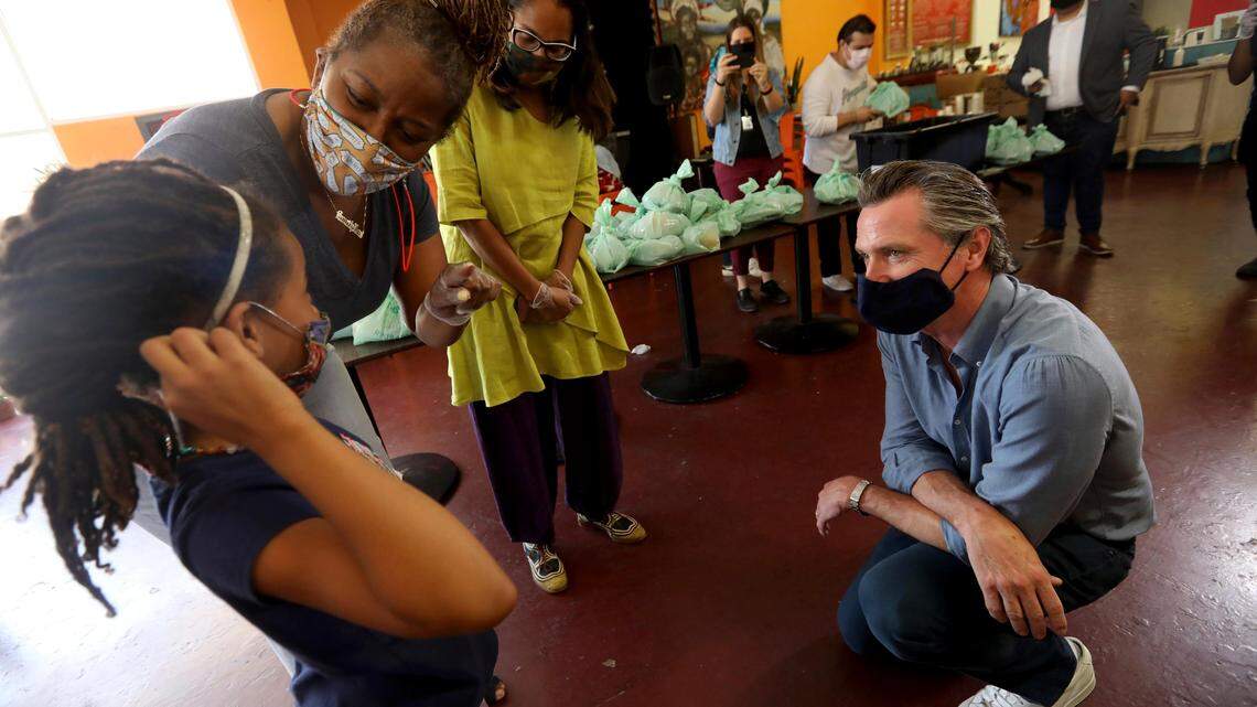 California Gov. Gavin Newsom, right, listens as he is introduced to Kirikou Muldrow, 8, by California Sen. Holly Mitchell and California Assembly Member Sydney Kamlager-Dove, right, during a visit to the Hot and Cool Cafe in Leimert Park in Los Angeles on Wednesday, June 3, 2020. The cafe has been providing meals for older adults during the coronavirus pandemic stay-at-home order. Muldrow has been helping pack the meals. Her mother is co-owner of the the cafe.