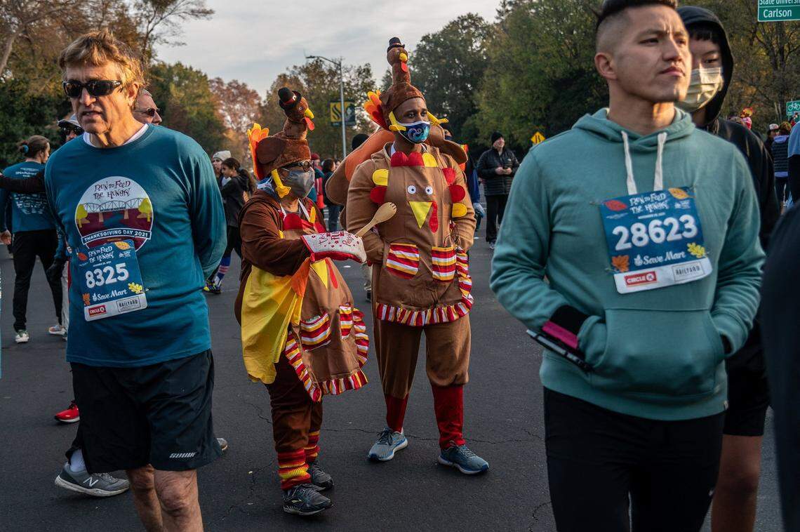 Shelia Mitchell, left center, and her son, Uriah Mitchell, right center, of Fair Oaks, dressed in turkey chef costumes and wore masks as they celebrated Thanksgiving Day at the 28th annual Run to Feed the Hungry on Thursday. They said they were happy to be outside and able to stay socially distanced as they wore masks to stay safe. Last year the race was canceled because of the pandemic.