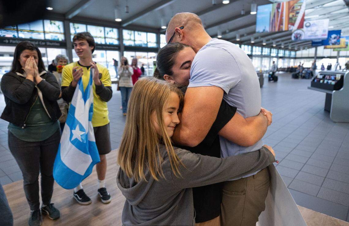 Navy Altom, 9, hugs her sister Taylor with her father Wade as mother Meredith and brother Luke wait at the Sacramento International Airport Terminal A on Tuesday, Nov. 26, 2024. Taylor is back from an 18-month Latter-Day Saints mission in Ecuador, just in time Thanksgiving. 