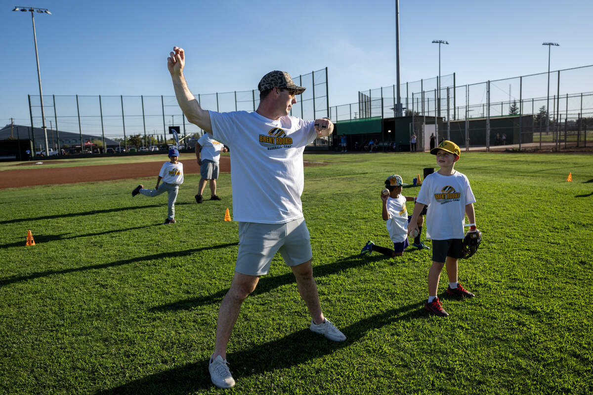 Athletics player Brent Rooker explains the proper position to throw a baseball to participants in his youth sports camp on Thursday at Depot Park.