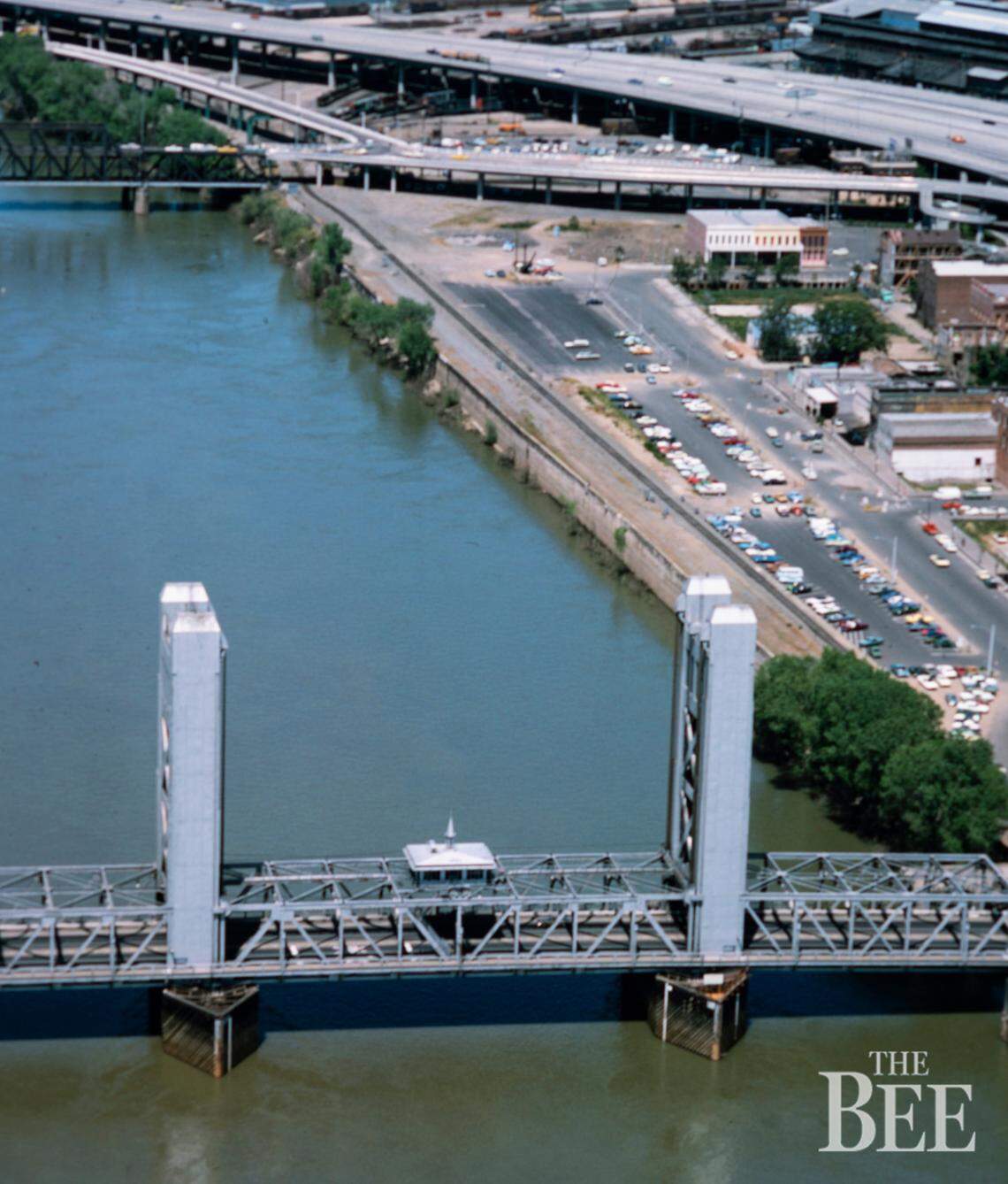 The Tower Bridge sports its original aluminum silver paint scheme in 1975, before its switch to golden hues, in an aerial photo of the Old Sacramento waterfront.