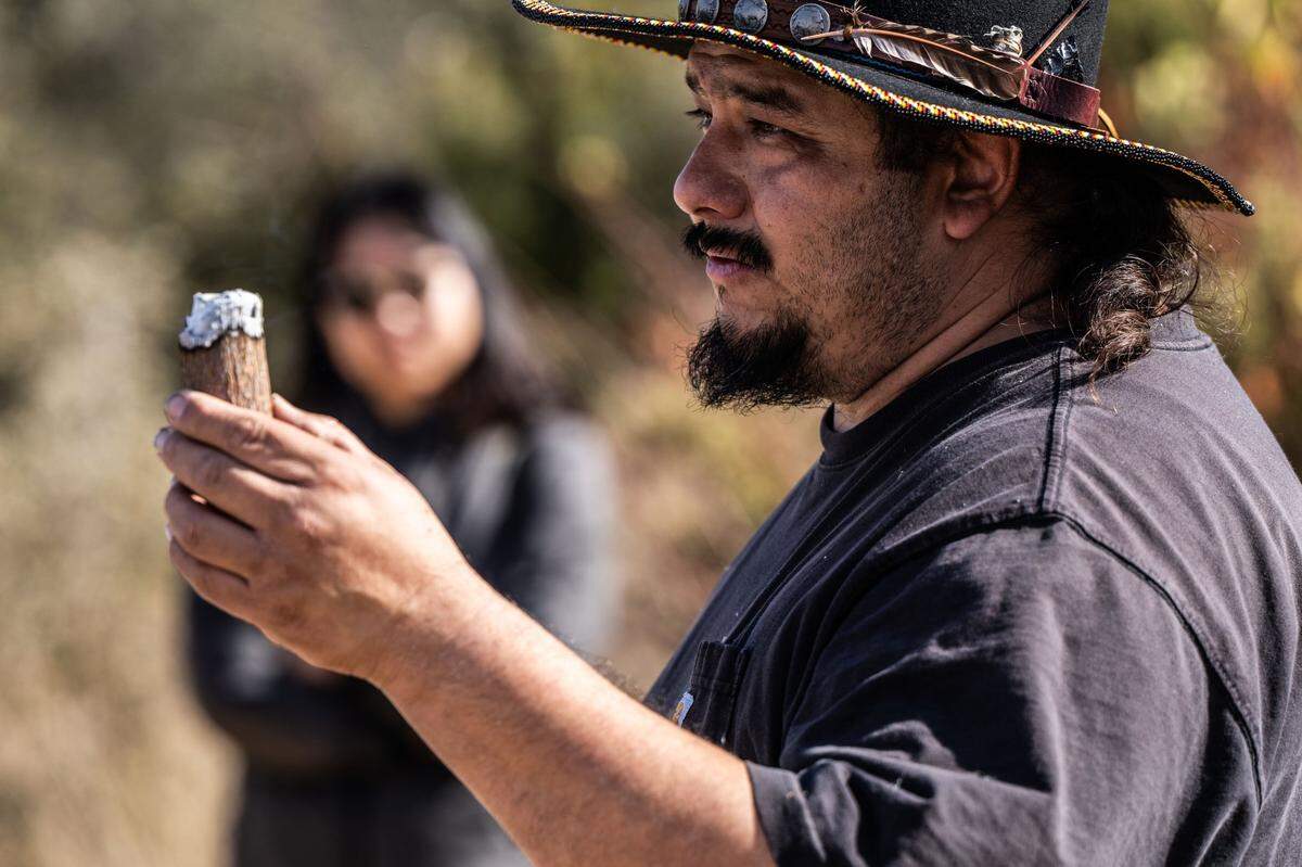 Danny Manning, a local firefighter and part of the Native American Maidu community, demonstrates Friday how his ancestors kept fires going by keeping an ember inside a piece of wood during the cultural burn.