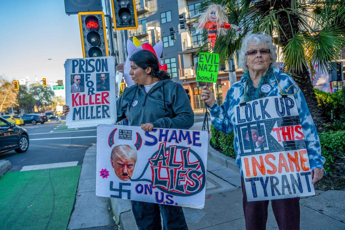 Yasmine Flores, left, and Deborah Earl, right, hold signs while attending a demonstration Monday at the intersection of 16th Street and Broadway in Sacramento against the U.S.-Israel war with Iran.