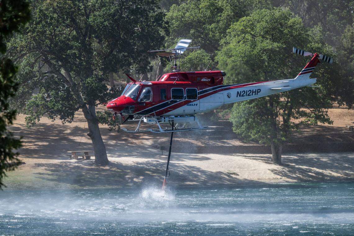 A Cal Fire helicopter picks up water from the Dyer Lake during the Crozier Fire in El Dorado County on Wednesday. Firefighters on radio said that it was too smokey for fixed-wing airdrops.