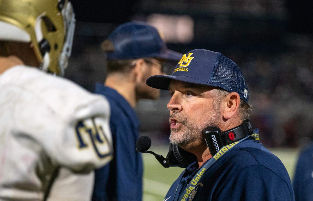 Nevada Union coach Brad Sparks discusses second half strategy with running back Rhyder Eelkema and other players during halftime against the Christian Brothers Falcons in Sacramento on Friday.