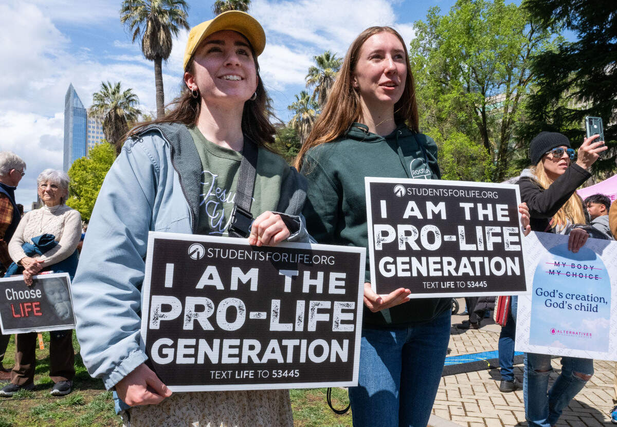Liz Franklin, 20, and Heidi Bowman, 17, both of the Central Valley, listen to speakers for the fifth annual California March for Life anti-abortion rally at the state Capitol on Monday.