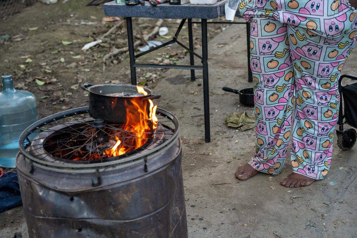 Elizabeth Williams cooks dinner for her encampment barefoot on a makeshift grill on March 26 in South Natomas. She said that when Sacramento police took her to jail in February it was cold and raining and that she hadn’t even put her shoes. Once she was released, she had to walk back to her encampment barefoot. Most of her belongings were trashed during the sweep and she is slowly acquiring new things.