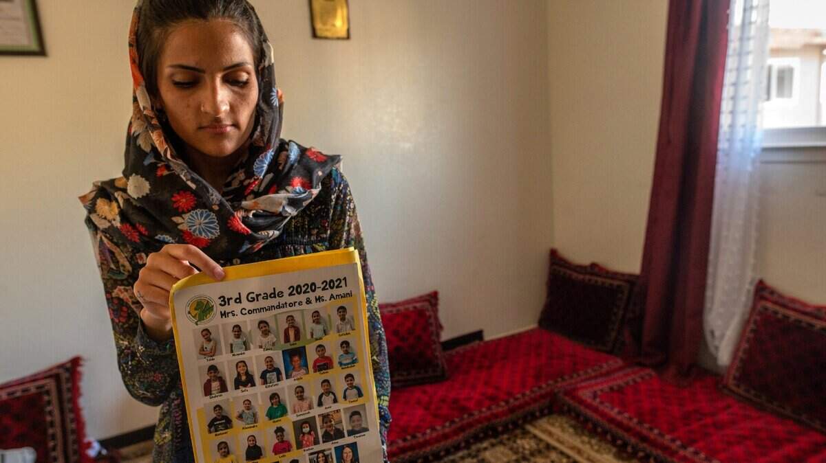 Behshta, 21, holds a school picture showing her youngest sister Neda, 9, second from left in top row, on Wednesday, Aug. 25, 2021, as she worries in their Arden Arcade bedroom whether his sisters will return from Afghanistan. She said the schools call every day asking when Neda, of Dyer-Kelly Elementary School and Sabrina, 15, of Encina High School, will return to class. The family explained that they are in hiding from the Taliban and cant get to the airport.