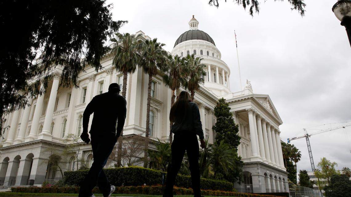 People walk near the state Capitol in Sacramento, Calif., Wednesday, March 18, 2020. In a precautionary effort to deal with the coronavirus, the Capitol and Legislative Office Building were closed to the public with only essential state workers and legislative employees allowed in until further notice, based on a “stay at home” directive issued by Sacramento County. (AP Photo/Rich Pedroncelli)