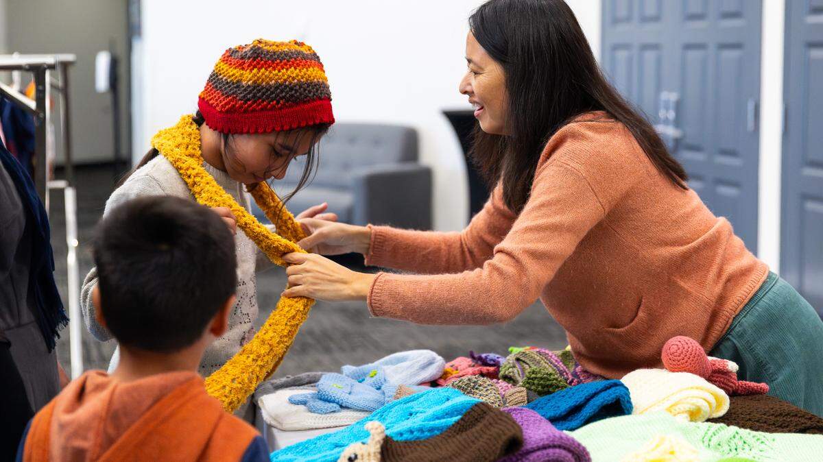 Starting Point volunteer Annette Dinh fits Khadija Akbari, 10, with a handmade hat and scarf to match the new coat she selected at Starting Point’s Warm Welcome clothing event in November.