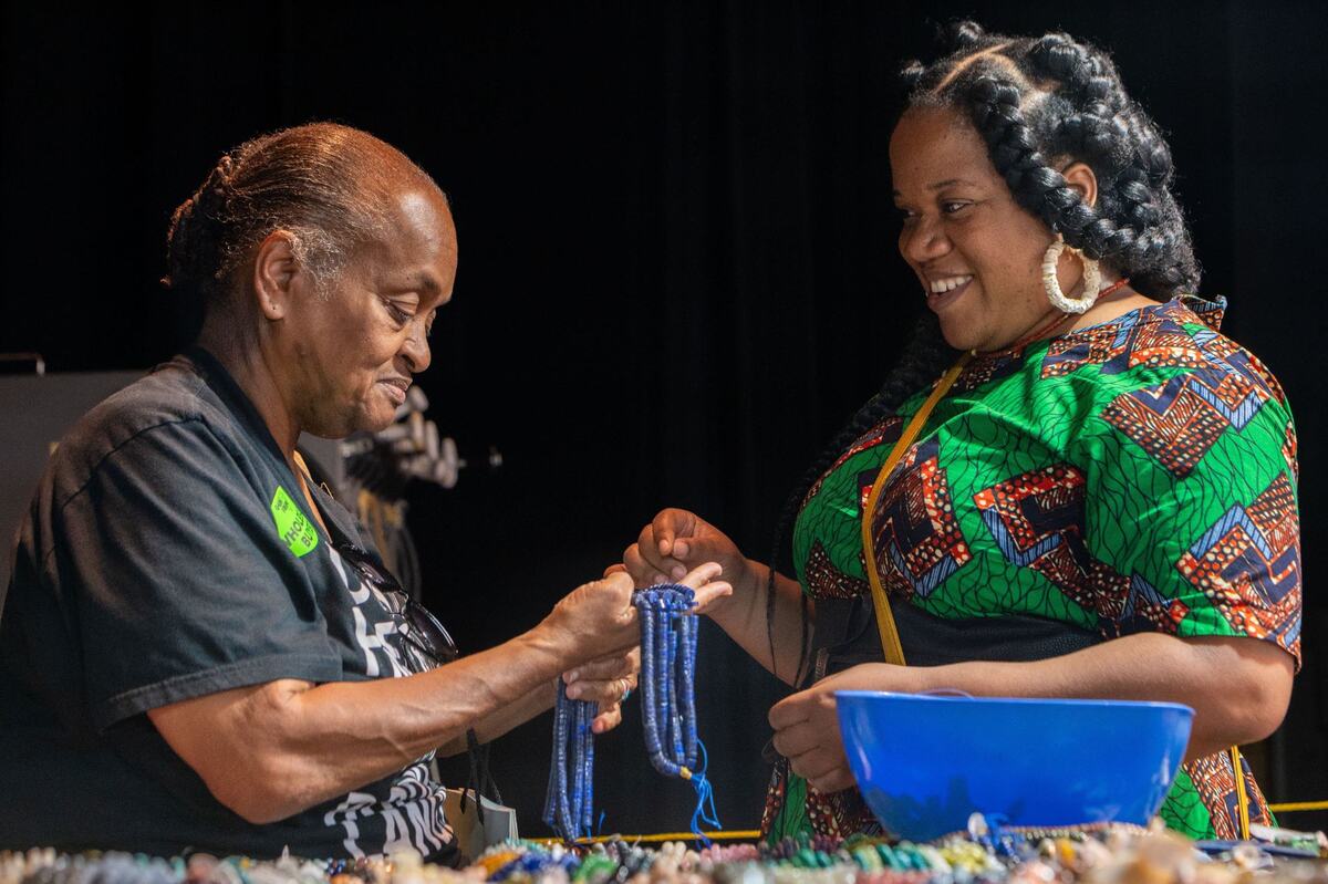 Lori Sparks, left, holds a string of beads while talking with her “beading goddaughter” Danielle Williams during the Gem Faire at the Scottish Rite Masonic Center in Sacramento on Friday, Aug. 2, 2024. “She does the more rugged stuff, and I do the more bling bling, shiny shiny stuff,” Sparks said.