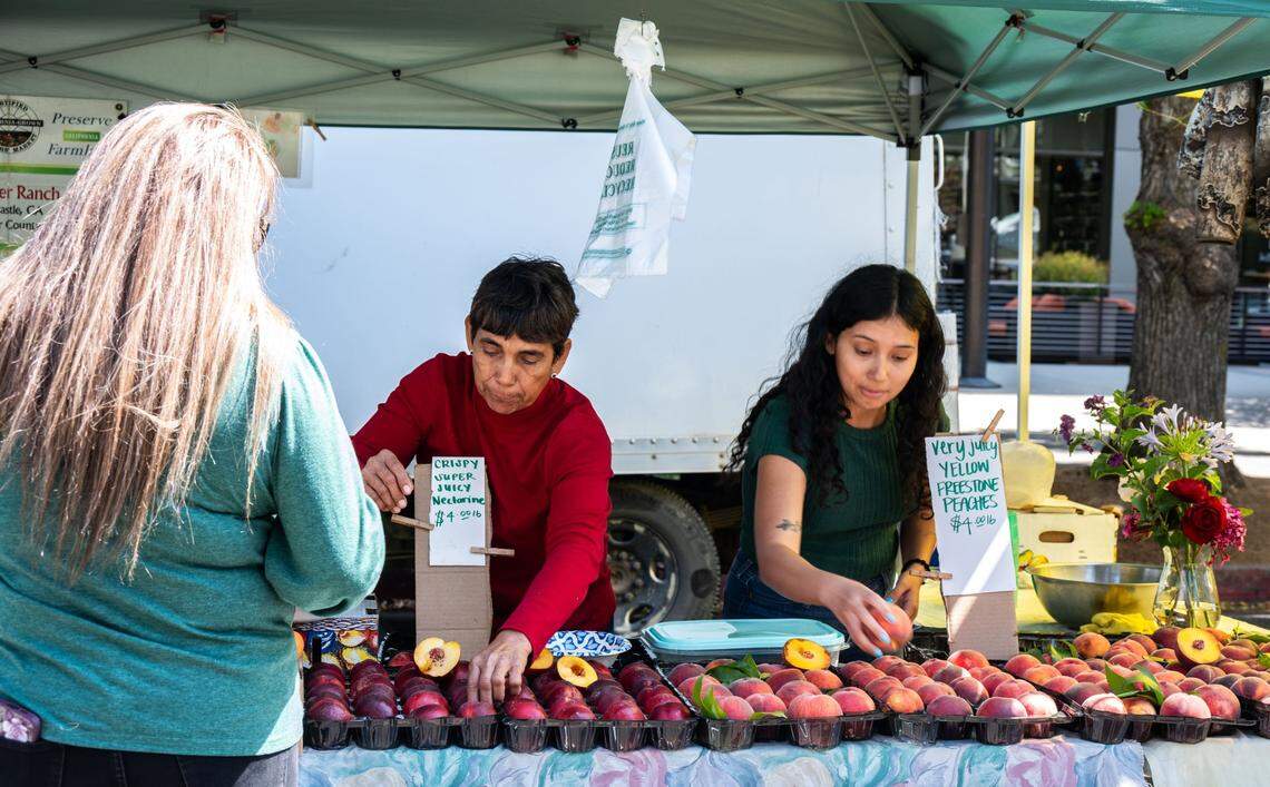 Magda Morgan, center, arranges produce with her daughter Kimberly, right, at their stand at the Capitol Mall Farmers’ Market on Wednesday.