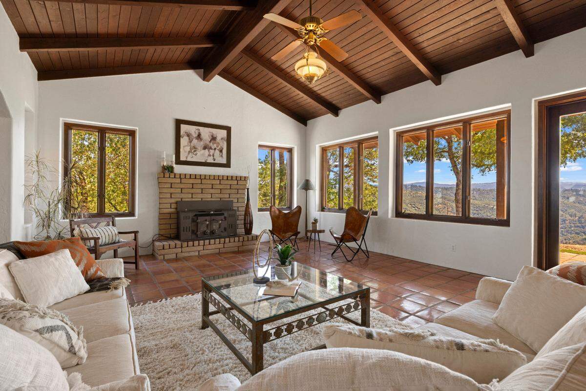The living room with vaulted wood-beamed ceilings and a wood-burning stove offers river and mountain views.