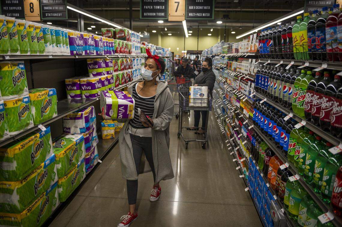 Customers grab toilet paper and other paper products while shopping on opening day at the new Raley’s in South Land Park in Sacramento on Wednesday, April 15, 2020. While the shelves were fully stocked, customers were limited to a maximum of two items per family per visit on essential items such as paper products.