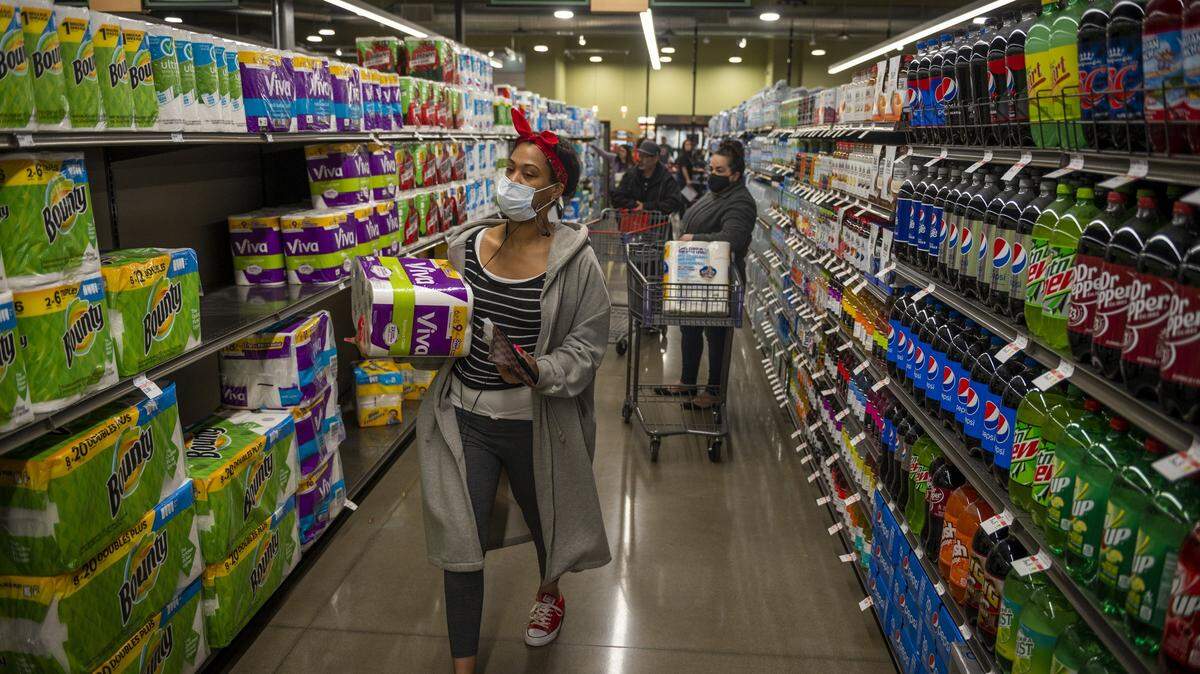 Customers grab toilet paper and other paper products while shopping on opening day at the new Raley’s in South Land Park in Sacramento on Wednesday, April 15, 2020. While the shelves were fully stocked, customers were limited to a maximum of two items per family per visit on essential items such as paper products.