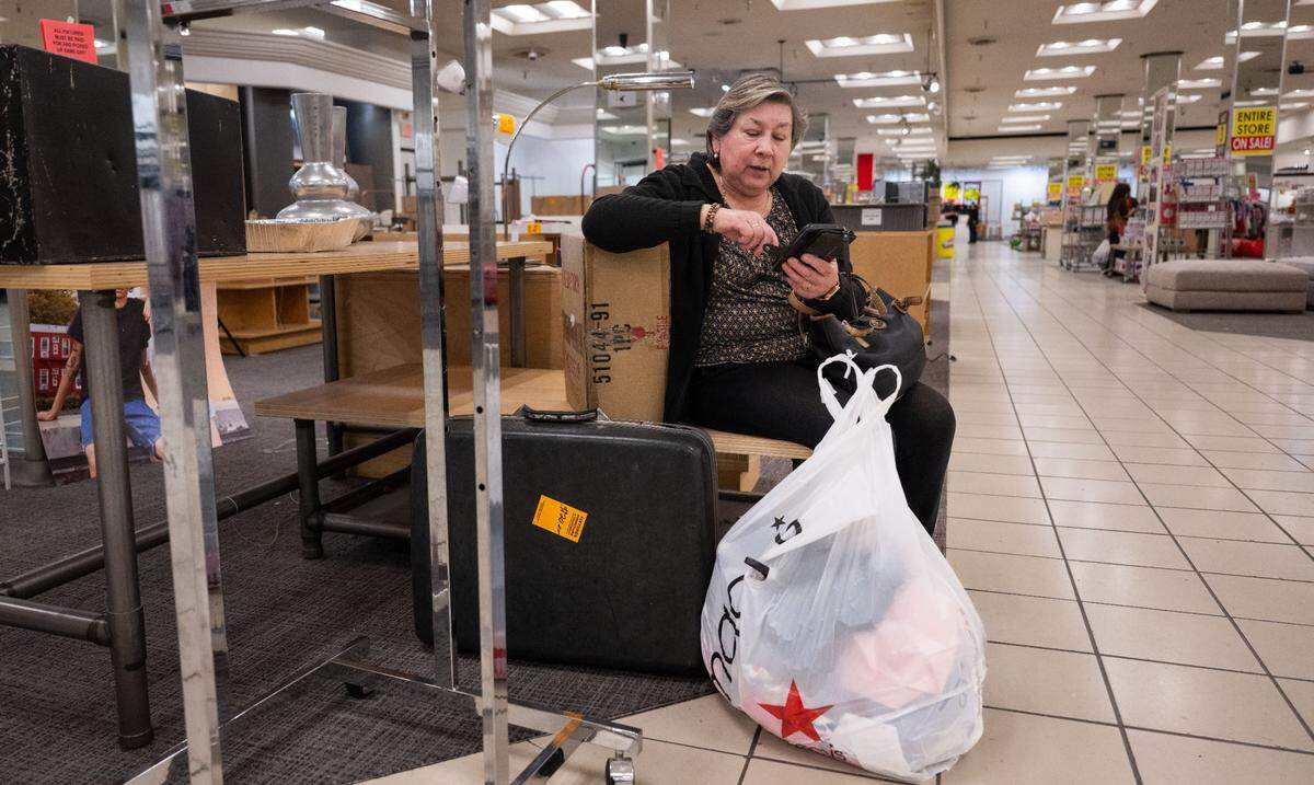 Aída Garzon, of Rancho Cordova, looks at her phone after buying some cloths for an upcoming trip at the Downtown Commons Macy’s store in Sacramento on Thursday.