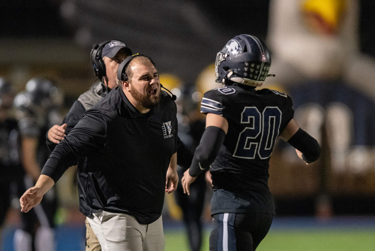 Vista del Lago coach Kyle Landes congratulates his offense, including running back Trevor Kaestner (20), after a PAT in the first quarter of the CIF Sac-Joaquin Section playoff quarterfinal Friday.