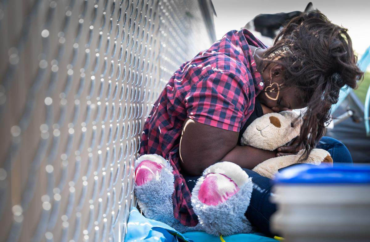 Arianne Hawkins of Sacramento hugs a stuffed animal Wednesday while resting against a fence in front of Safe Stay Community, a tiny homes village set up by the County near Florin and Power Inn roads. Hawkins is one of the homeless residents that have been staying near the shelter for the past year, waiting for it to open.