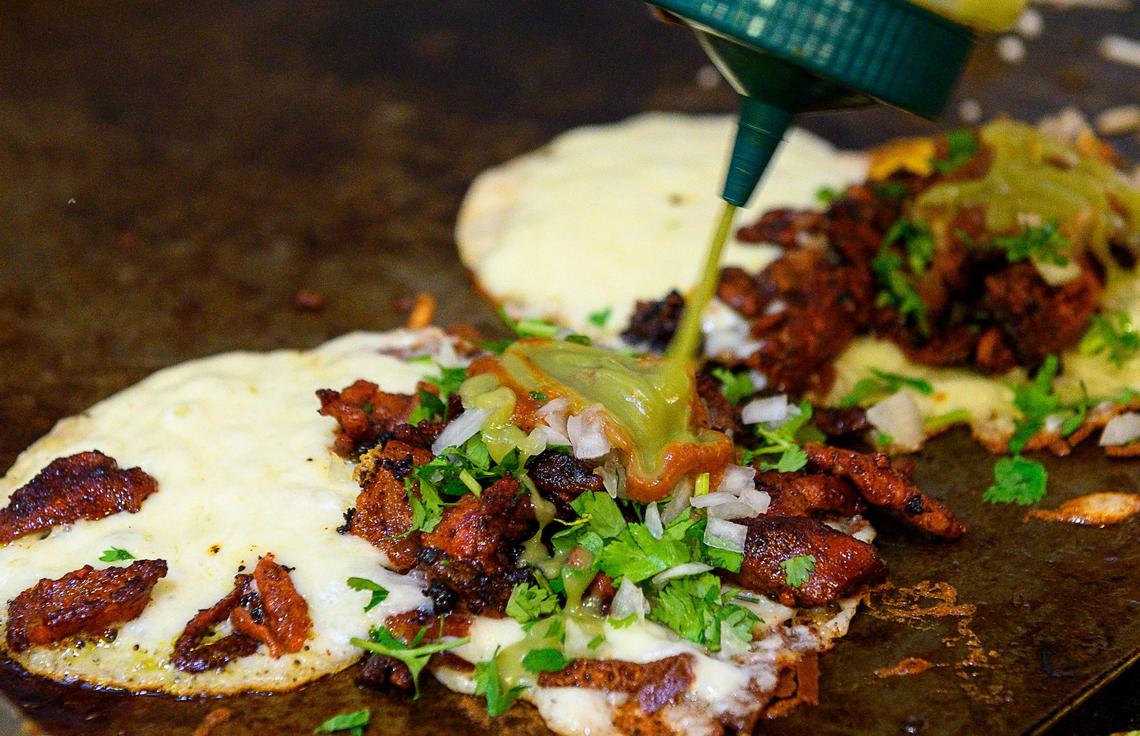 Corn tortillas are grilled with cheese and adobada, onions, cilantro, avocado sauce and a chili sauce at Chandos on Monday, Dec 30, 2019 in West Sacramento.