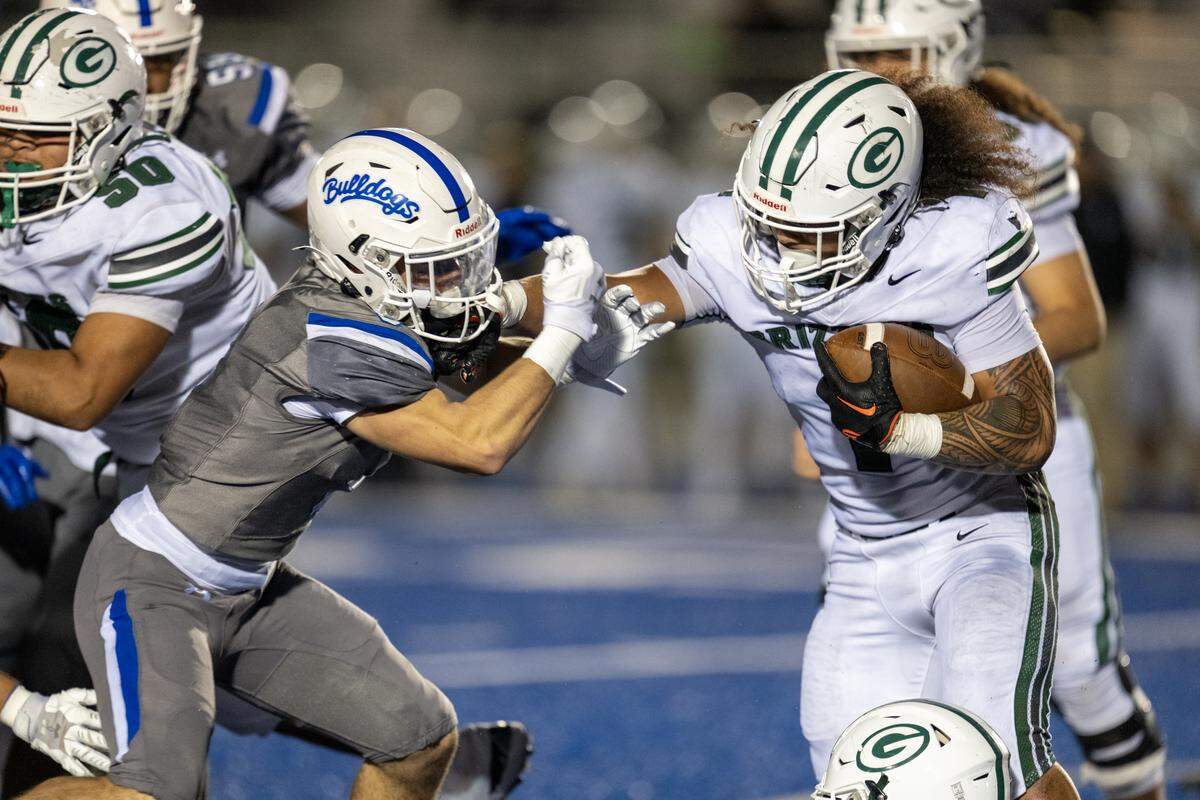 The Granite Bay Grizzlies’ Isaiah Ene stiff-arms the Folsom Bulldogs’ Dylan Wolfe (8) for a short gain in the second half on Friday, Oct. 31, 2025, in Folsom.