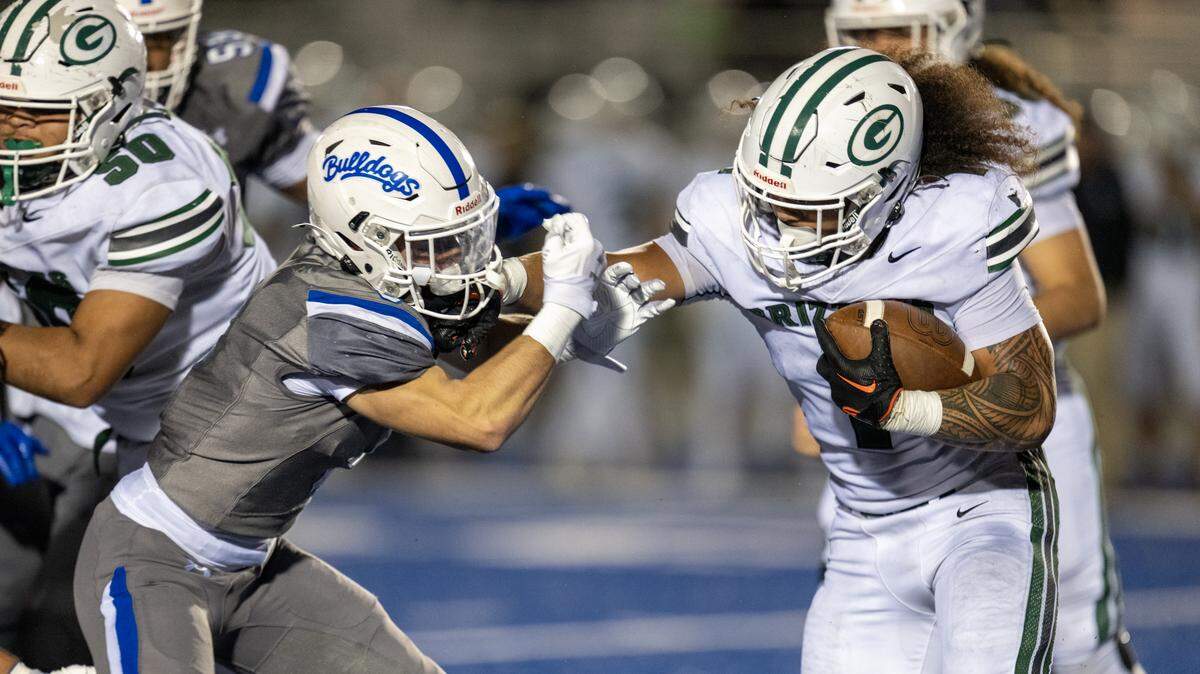 The Granite Bay Grizzlies’ Isaiah Ene stiff-arms the Folsom Bulldogs’ Dylan Wolfe (8) for a short gain in the second half on Friday in Folsom.