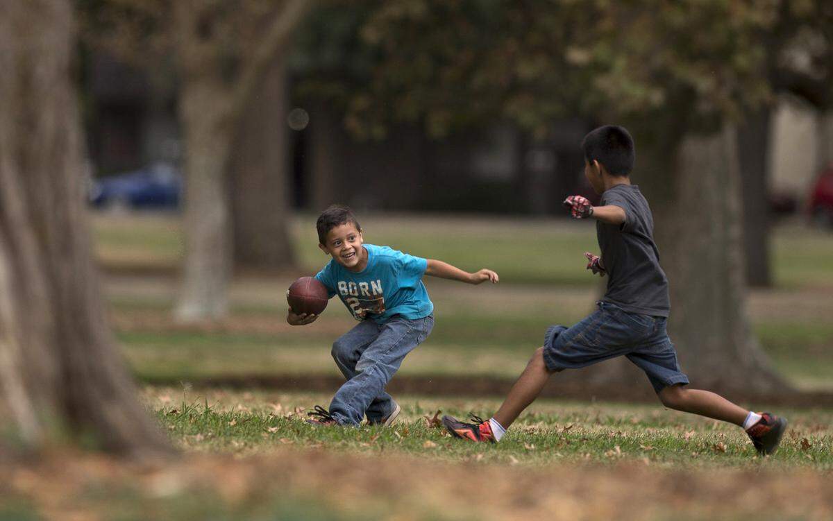 Marcos Gutierrez, 6, dodges an on coming tackler, Alfonzo Romero, 11, during a pickup football game at Southside Park in October 2015.
