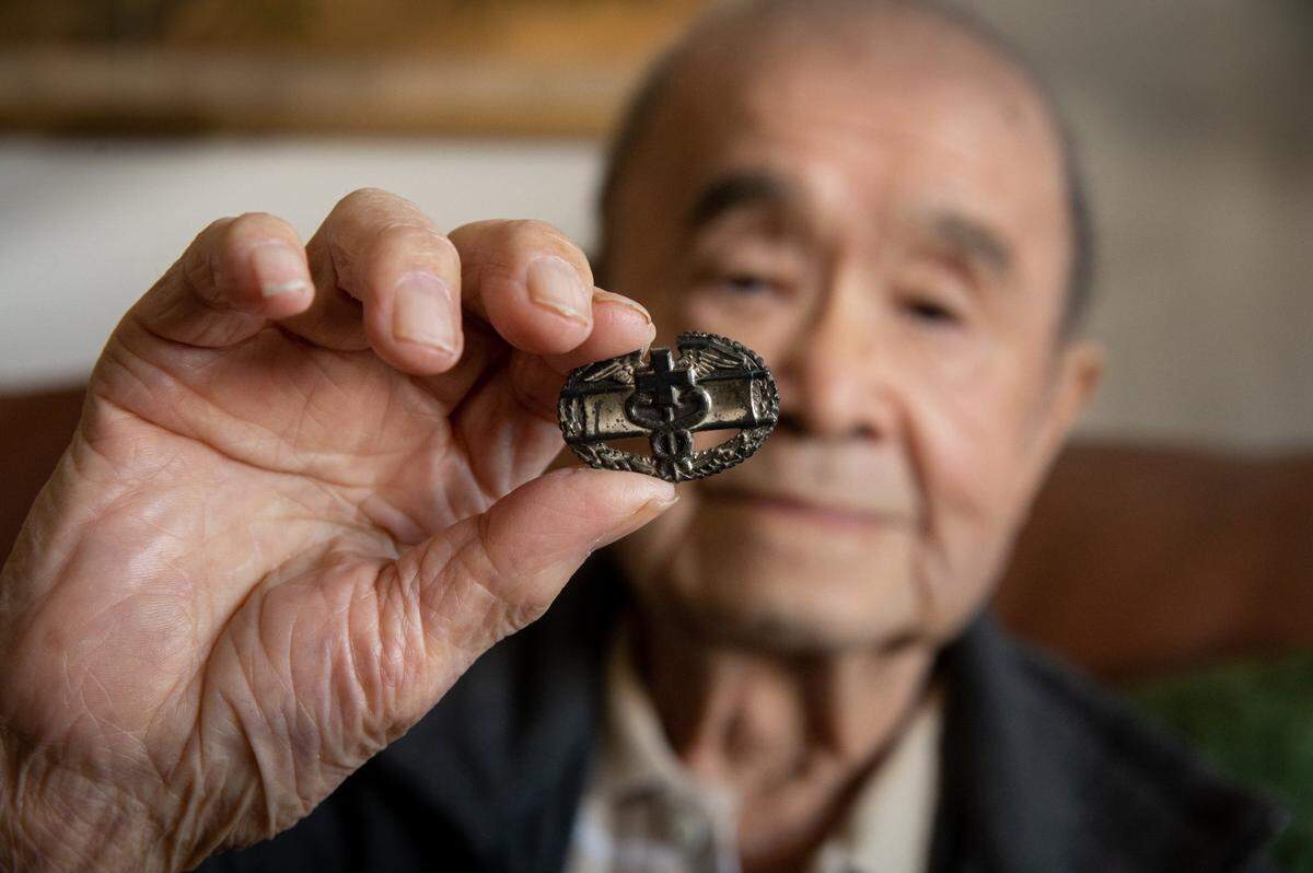 Seiki Masaki George Hamai, 100, holds the medic pin he wore during combat in the battlefields of Italy and France with the Army’s all-Japanese American 442nd Combat Regiment during World War II. “I was shot at for giving first aid, but I never got wounded – got lucky,” said Hamai, who was awarded a Bronze Star for bravery. He reflects on his service in his Sacramento home earlier this month.