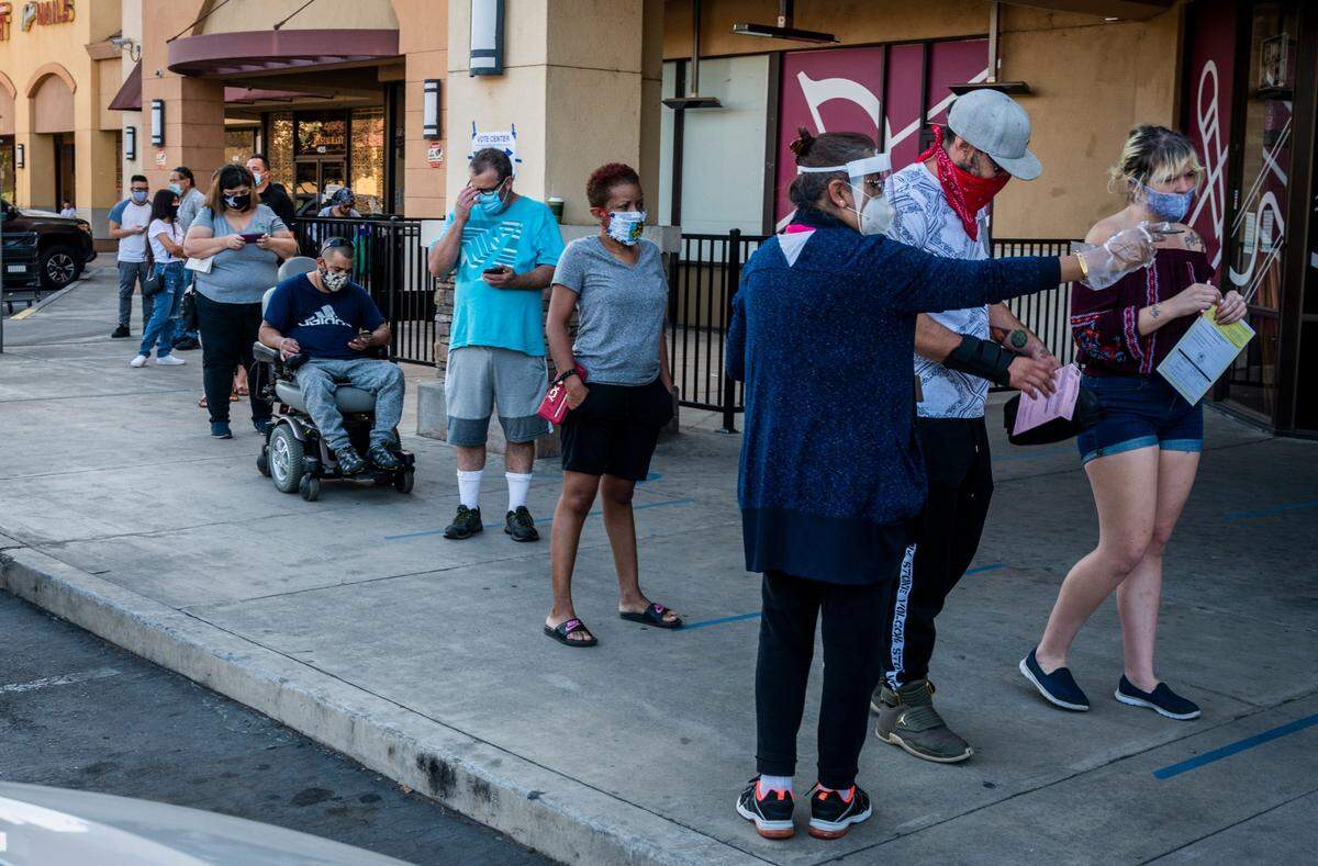 An elections worker directs people waiting in line to vote outside a vote center at KP International Market in Rancho Cordova on Tuesday, Nov. 3. The location was one of 10 sites Sacramento County elections officials said had long wait times on Election Day. They encouraged voters to consider voting at one of the 74 other locations.
