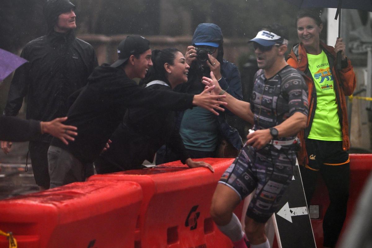 Janet Carmona, center, high-fives her husband Edgar Corral, of Los Gatos, with her son Evan, 15, as he runs towards Old Sacramento during the Ironman California triathlon on Sunday.