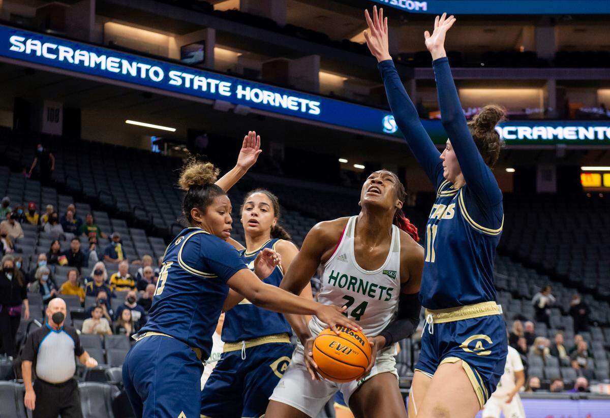 UC Davis Aggies guard Evanne Turner (15) and guard Sage Stobbart (11) put pressure on Sacramento State Hornets center Isnelle Natabou (24) in the post during the first quarter on Tuesday, Nov. 23, 2021 during a nonconference basketball game at the Golden 1 Center in Sacramento. The Aggies won 75-46.