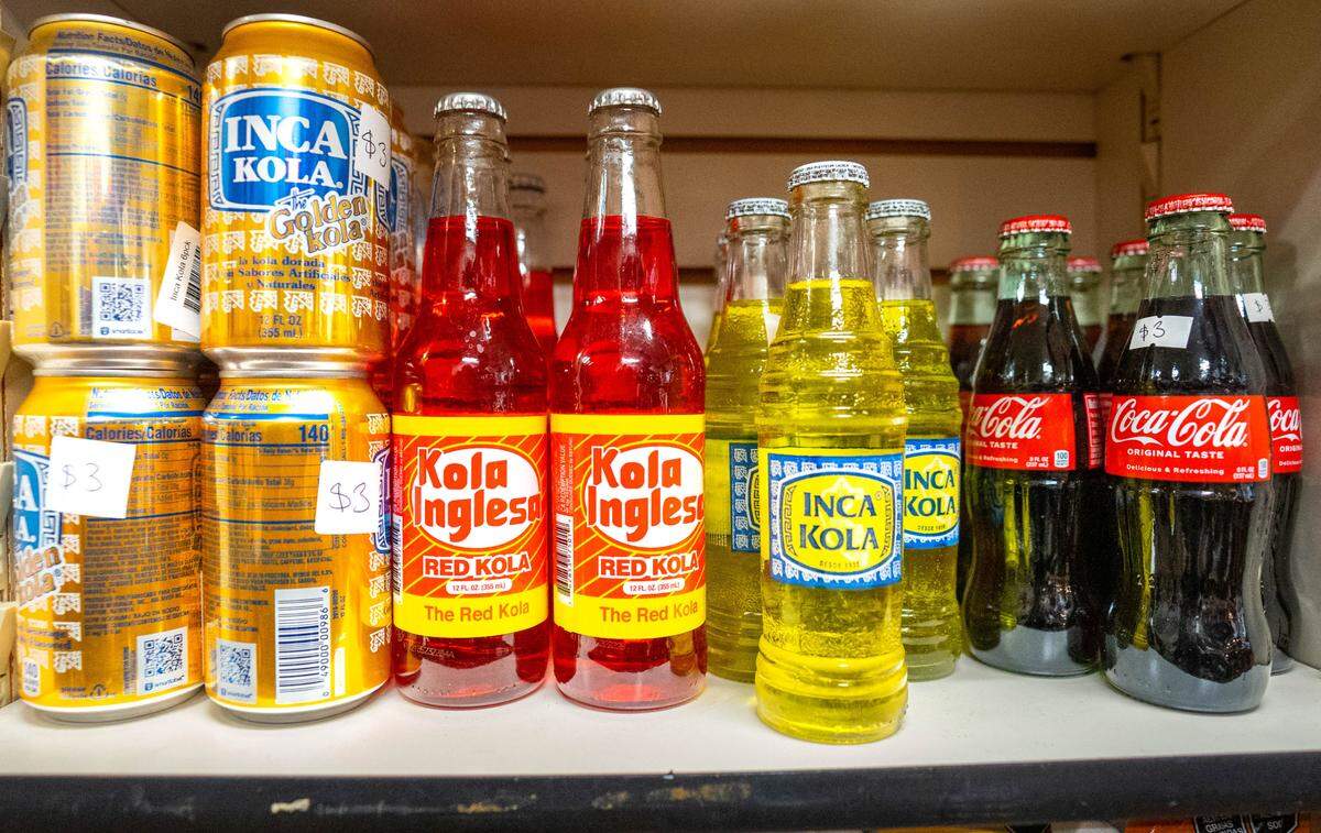 Conocidos refrescos peruanos se alinean en los estantes de Mi Tiendita Munaycha junto con otros alimentos y especias únicas de Perú.