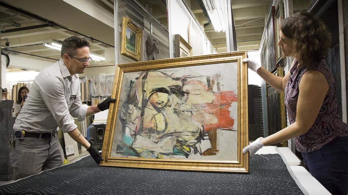 “Woman-Ochre,” a painting by Willem de Kooning, is readied for examination by University of Arizona Museum of Art staff Nathan Saxton, left, and Kristen Schmidt in Tucson, Ariz., in August 2017. After the painting was stolen in 1985 from an Arizona museum, staff clung to the hope that it would turn up one day. The oil painting is finally back home and ready to be shown. It will be the centerpiece of an exhibition opening Oct. 8, 2022, until May 2023 at the University of Arizona Museum of Art.