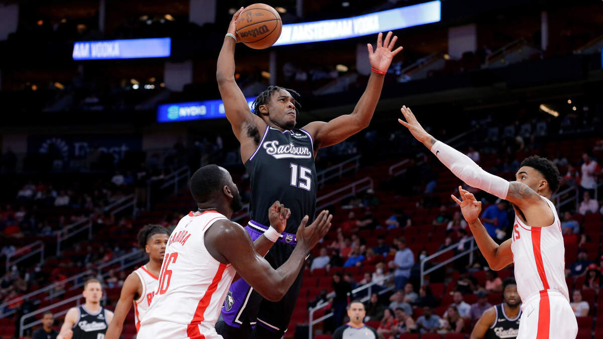 Sacramento Kings guard Davion Mitchell (15) goes up for a dunk over Houston Rockets forwards Usman Garuba, left, and Kenyon Martin Jr., right, during the first half of an NBA basketball game Wednesday, March 30, 2022, in Houston. (AP Photo/Michael Wyke)