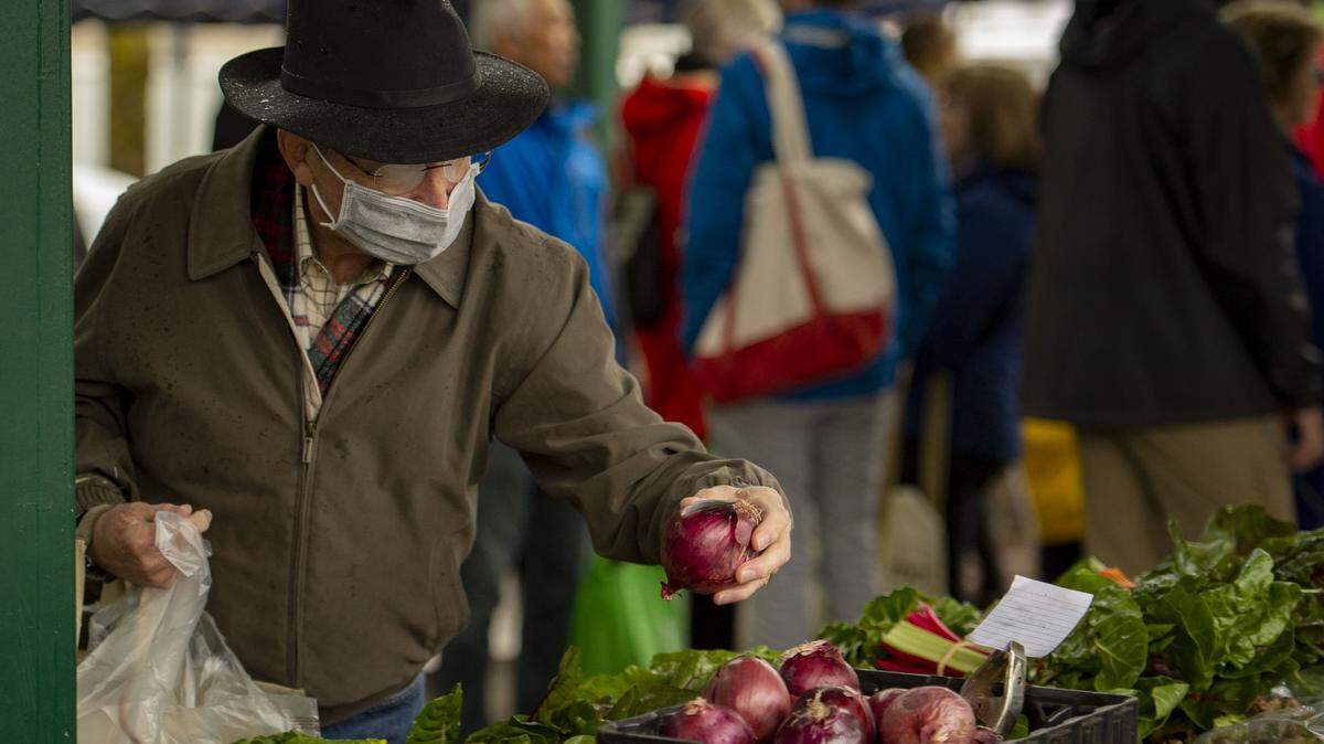 A Davis resident picks out produce at the Davis Farmers Market on Saturday, March 14, 2020, while wearing a medical mask to protect himself and in an effort to help slow the spread of the global coronavirus pandemic.