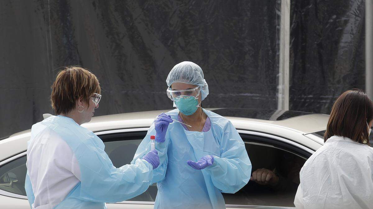 FILE - In this March 12, 2020, file photo, health care personnel test a person in the passenger seat of a car for coronavirus at a Kaiser Permanente medical center parking lot in San Francisco. The Associated Press has found that the critical shortage of testing swabs, protective masks, surgical gowns and hand sanitizer can be tied to a sudden drop in imports of medical supplies. (AP Photo/Jeff Chiu, File)