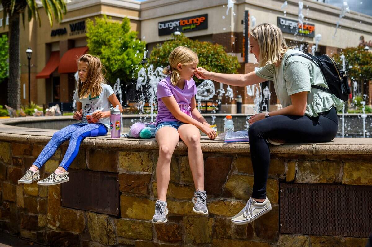 Nanny Kristna Lavor, right, wipes Laurens nose as Kaylie, left, holds a bag of baby carrots at Fountains at Roseville on Monday, May 18, 2020. As people returned to the center’s retail shops after it was allowed to reopen during the coronavirus pandemic, many people chose not to wear masks.