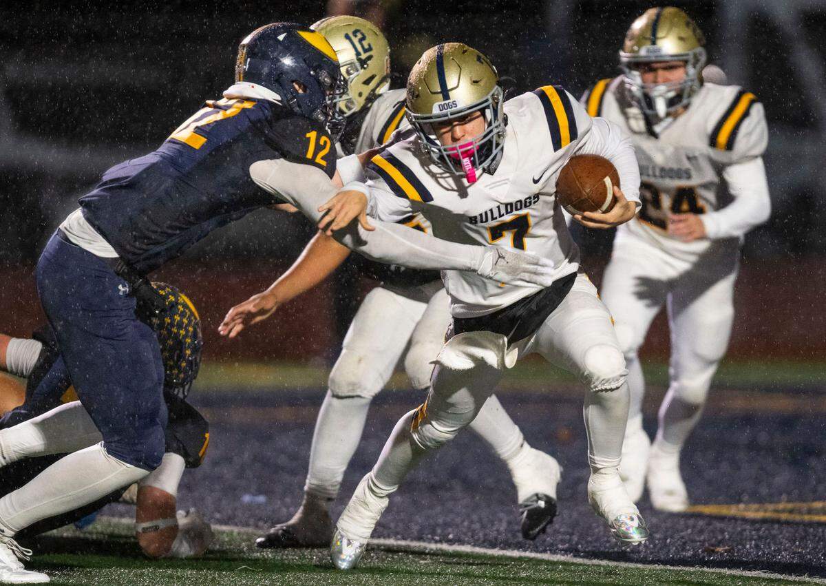 Turlock Bulldogs quarterback Scout Silva (7) is brought down near the line of scrimmage by the Oak Ridge Trojans’ Justen Womack (12) in the third quarter of a Sac-Joaquin Section semifinal playoff game on Friday, Nov. 22, 2024, in El Dorado Hills.
