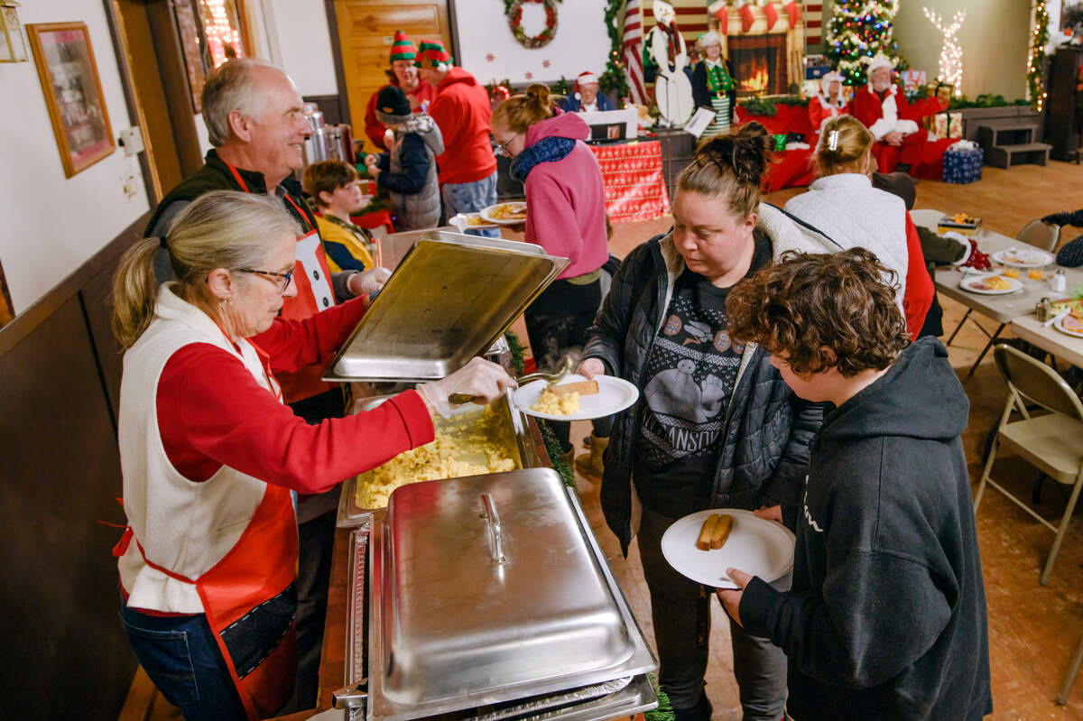 Jody Westfall of Somerset, left, serves breakfast to Champaygne Tafoya of Vallejo, and Andrew Soriano, 11, of Somerset during the Breakfast with Santa event at the Fireman’s Hall in Somerset earlier this month.