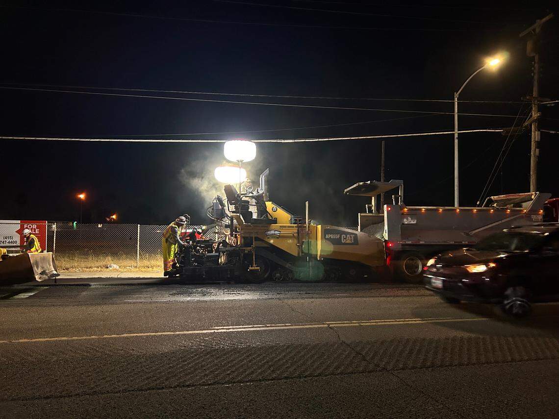 A construction crew works to repave part of Martin Luther King Jr. Boulevard as cars pass close by. It is illegal to exceed posted speeds at construction sites, even if workers are not present.